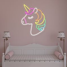 a pink room with a white bed and a neon unicorn head on the wall above it