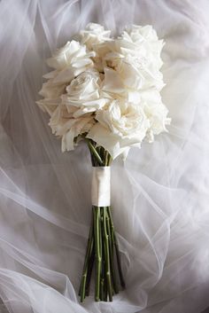 a bouquet of white flowers sitting on top of a bed covered in tulle fabric