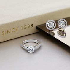 two diamond rings sitting on top of a book next to a pair of engagement rings