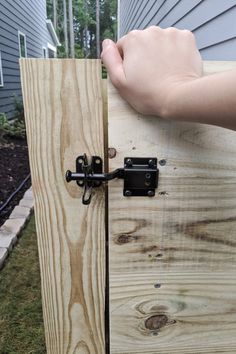 a person holding onto a wooden door with black latches on it's side