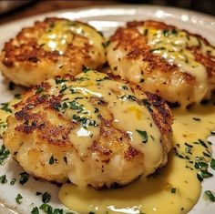 three scallops covered in cheese on a white plate