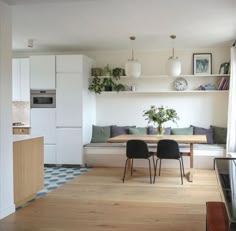 a kitchen and living room with white walls, wood floors and open shelving on the wall