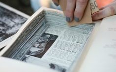 a person is holding an open book with some type of paper on it and reading