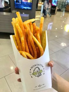 a person holding up a paper bag filled with french fries