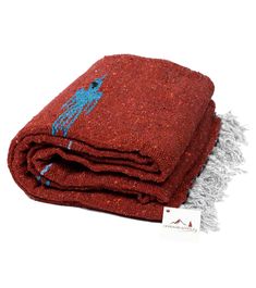 a red and blue blanket sitting on top of a white table next to a tag