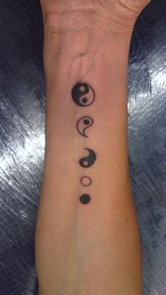 a wrist tattoo with three yin - yang symbols on it