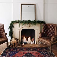 a living room filled with furniture and a fire place covered in greenery next to a mirror