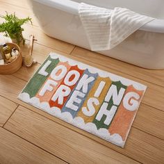 a bathroom rug that says looking fresh on the floor next to a bathtub and toilet