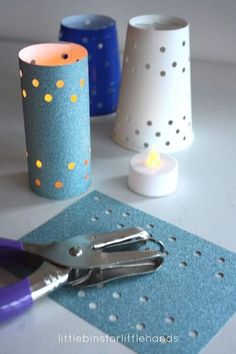 a pair of scissors sits on top of a table next to some paper cups and candles