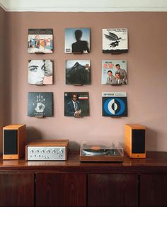 an entertainment center with speakers, record players and pictures on the wall above it in a living room