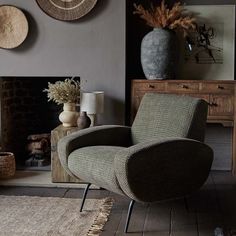 a living room with a chair, table and two vases on the fireplace mantel