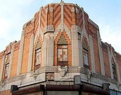 an old brick building with a clock on the top of it's corner in front of a cloudy blue sky