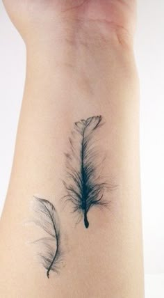 a feather tattoo on the back of a woman's arm