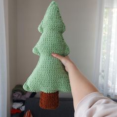 a crocheted green christmas tree hanging from a hook on a wall in a living room