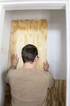 a man standing in front of a wooden board with his hands up to the ceiling