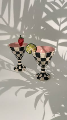 two black and white checkered cups with lime slices on them, one has a strawberry in the middle