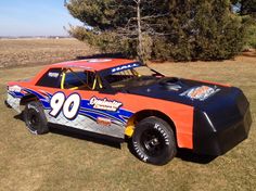 an orange and blue race car parked in the grass