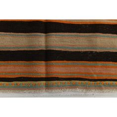 an orange, brown and green striped rug with fringes on the bottom half of it