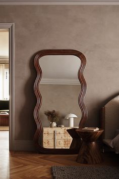 a large mirror sitting on top of a wooden floor next to a dresser and chair