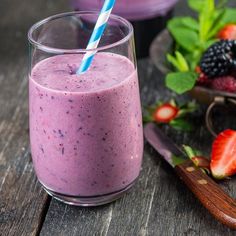 a smoothie in a glass with a blue and white striped straw next to it