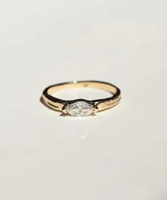 a gold ring with a diamond in the center on a white surface, close up