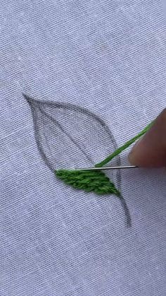 someone is using scissors to cut the green thread into small pieces on top of fabric