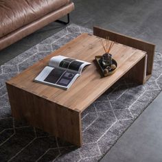 a wooden table sitting on top of a rug next to a brown leather couch and chair