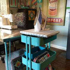 a sewing machine sitting on top of a wooden table next to a blue cart filled with fabric