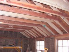 an unfinished room with wooden beams and windows