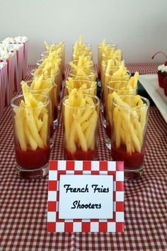 french fries are arranged in small glasses on a checkered tablecloth with cupcakes