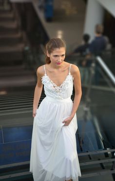 a woman in a white dress standing on some stairs