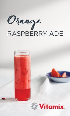 an orange raspberryade drink in a glass next to a bowl of strawberries