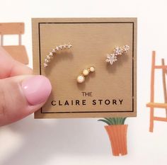 a person holding up a pair of earrings in front of a card with the words, the claire story on it