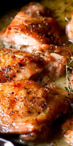 three pieces of chicken cooking in a skillet