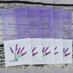 four lavender colored napkins with embroidered flowers on them