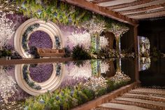 a room with flowers and plants on the wall next to a mirror reflecting it's reflection