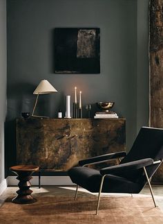 a living room with a chair, table and lamp on the sideboard in front of it