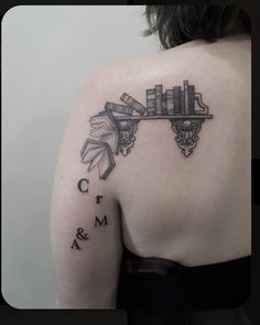 the back of a woman's shoulder with books and letters tattooed on her arm