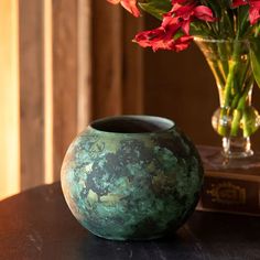 a vase filled with red flowers sitting on top of a table next to a book