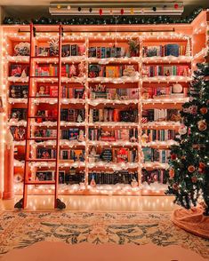 a christmas tree is in front of a book shelf with books on it and lights