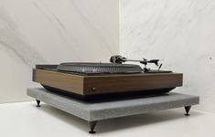 an old - fashioned record player sits on a bench in front of a marble wall