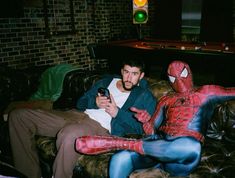 a man sitting on top of a couch next to a spider man