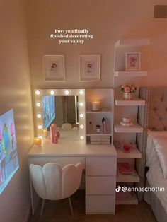 there is a vanity with lights on it and a mirror in the corner, next to a bed