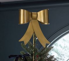 a gold bow on top of a christmas tree