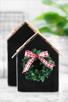 a small house with a wreath on top of it and a plant in the background