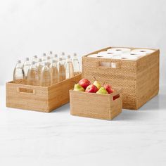 two wicker baskets with apples and water bottles in them on a white surface next to each other