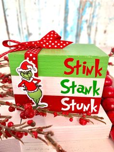 a green and red box sitting on top of a wooden table next to some berries