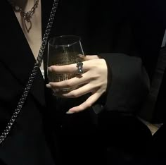 a woman holding a wine glass in her right hand and wearing a chain around her neck