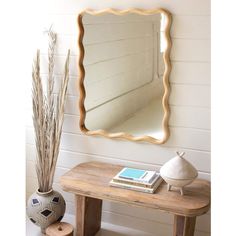 a mirror sitting on top of a wooden table next to a vase