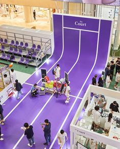 people are standing around in an indoor shopping mall with purple walls and white lines on the floor